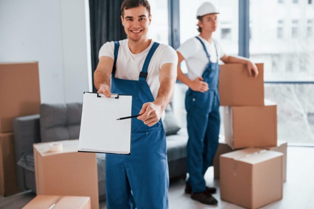 Document to sign – two young movers in blue uniforms working indoors during a move