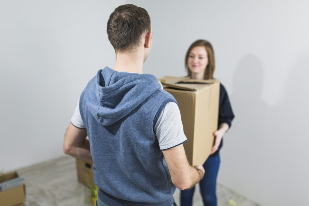 Faceless couple carrying moving box together – teamwork during a home relocation