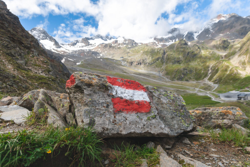 Alpine hiking trail in Austria marked with a painted Austrian flag on a rock along the route