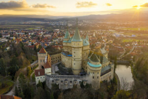 European medieval castle at Bojnice, Slovakia, with sun low above the horizon. Chateau overlooking town in soft morning light.