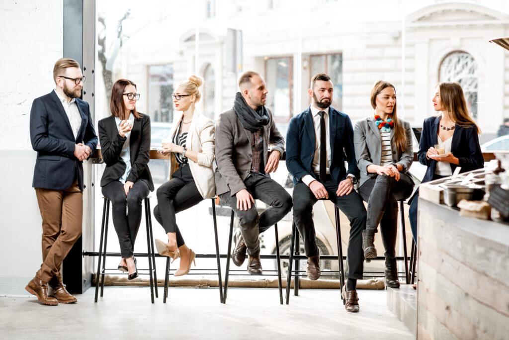Business people talking together sitting in a row near the window in the cafe