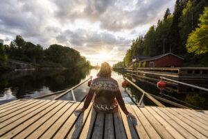 Finland, Kajaani, Man sitting on jetty, watching sunset, rear view