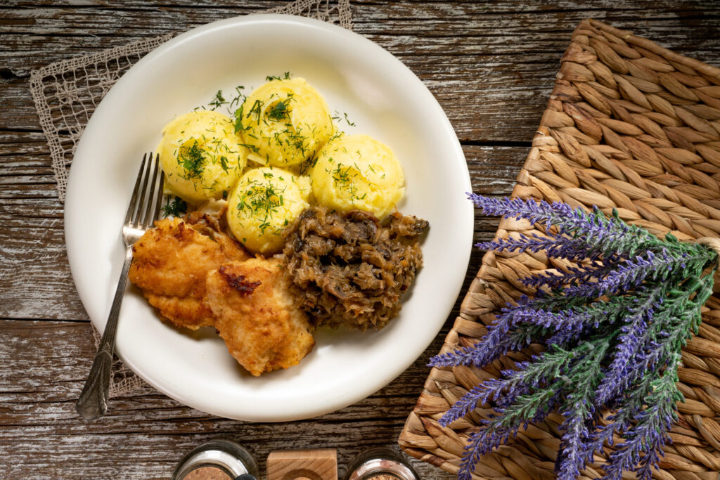 Fried cod fillet served with boiled potatoes and fried sauerkraut with mushrooms.