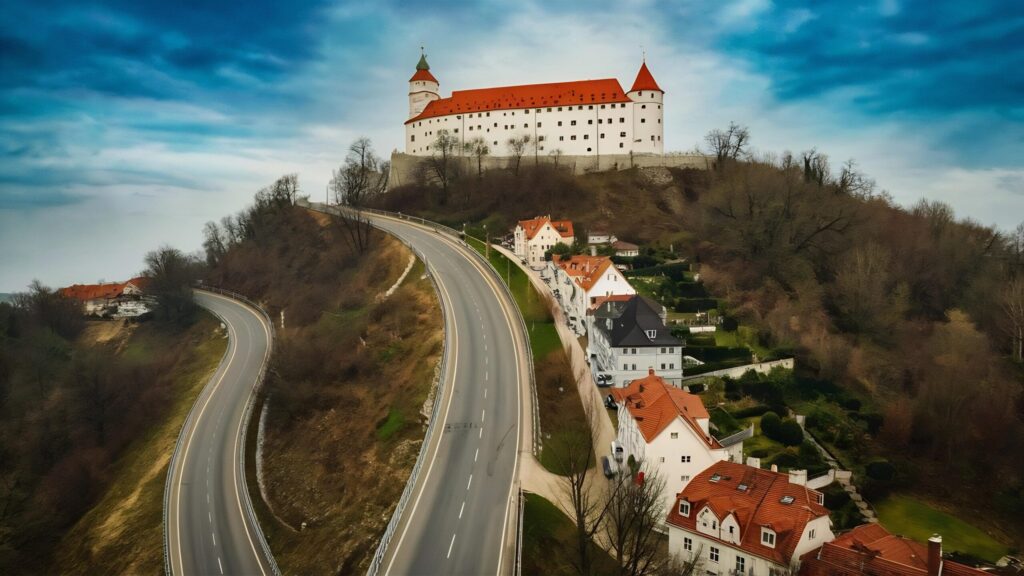 High-angle shot of a road descending a hill beside Vaduz Castle in Liechtenstein – scenic mountainous view