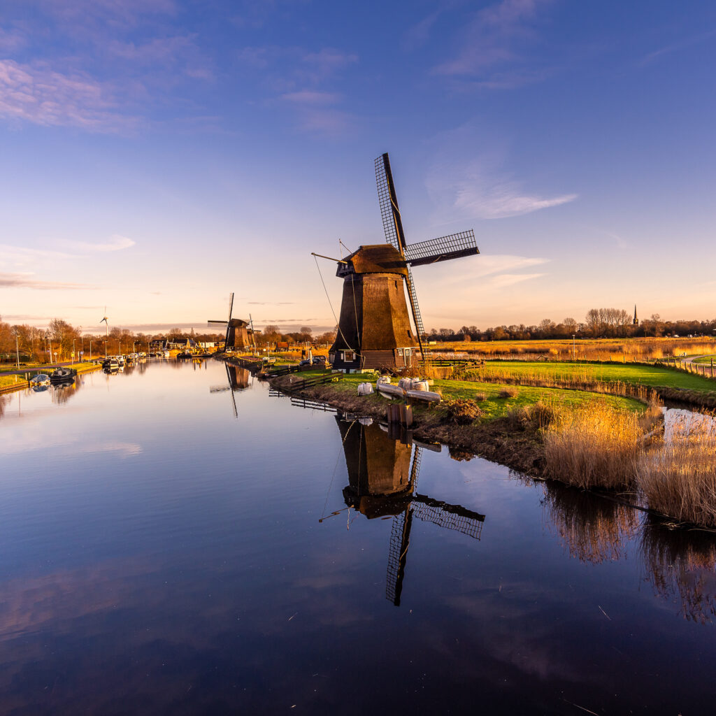 An eerie scenery of old windmills at Kinderdijk by the lake in the starry night in Alkmaar city, Netherlands