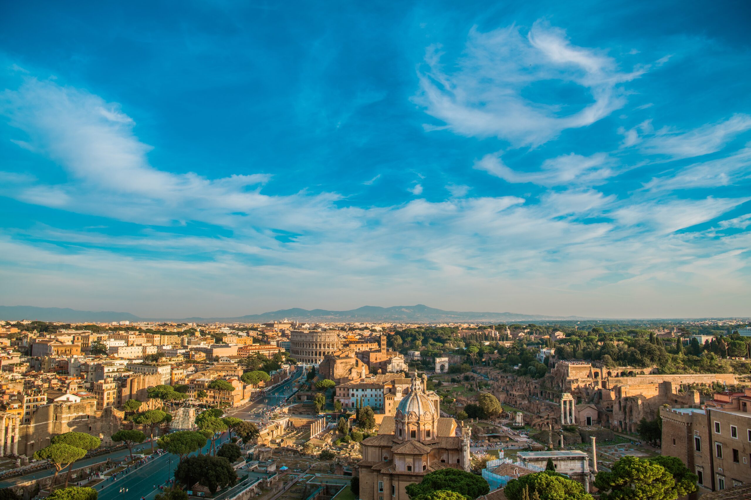 Rome Italy Summer Time Cityscape. Colosseum and the Roman Forum. Popular European Destination. Clear Sky with Some Clouds.