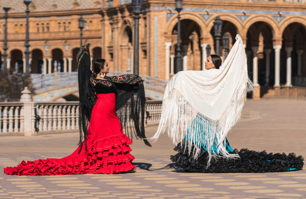 Two hispanic women in flamenco dress dancing on the Spain square in Seville