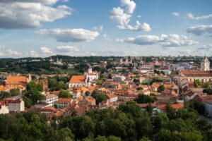 The Vilnius city surrounded by buildings and greenery under sunlight and a cloudy sky in Lithuania