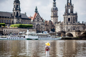 Young woman tourist in yellow hat standing back and enjoying great view on the old town of Dresden, Germany