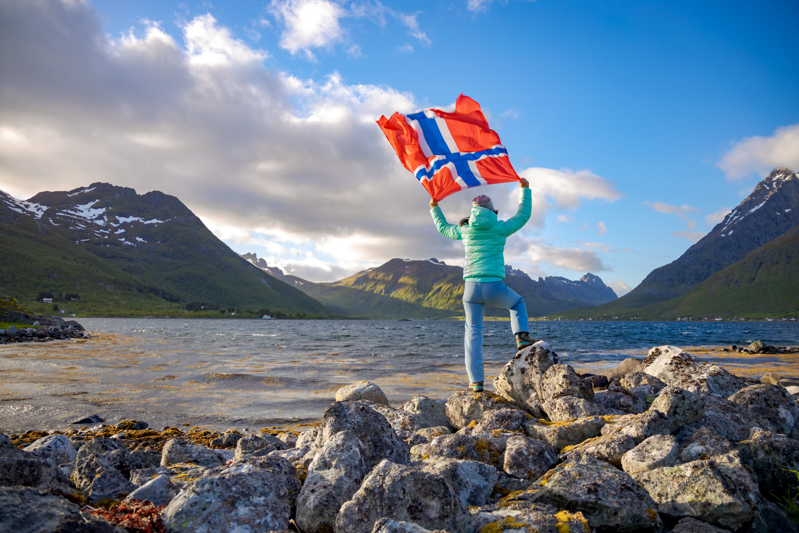 Woman with a waving flag of Norway on the background of nature