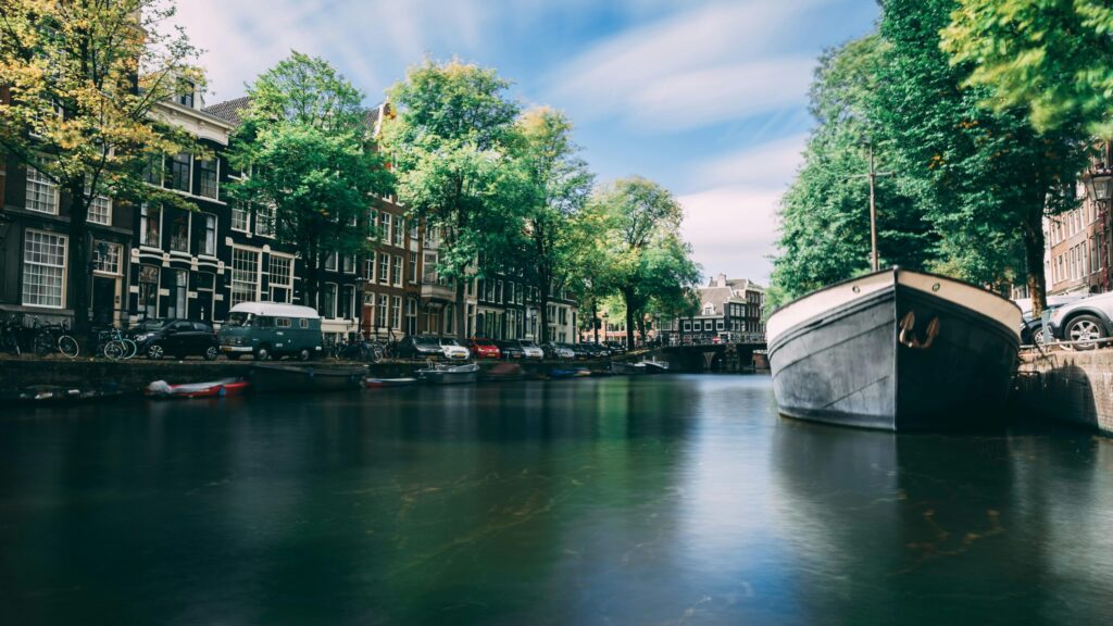 Scenic Amsterdam canal lined with historic brick houses and a parked moving van – illustrating moving from the UK to the Netherlands.