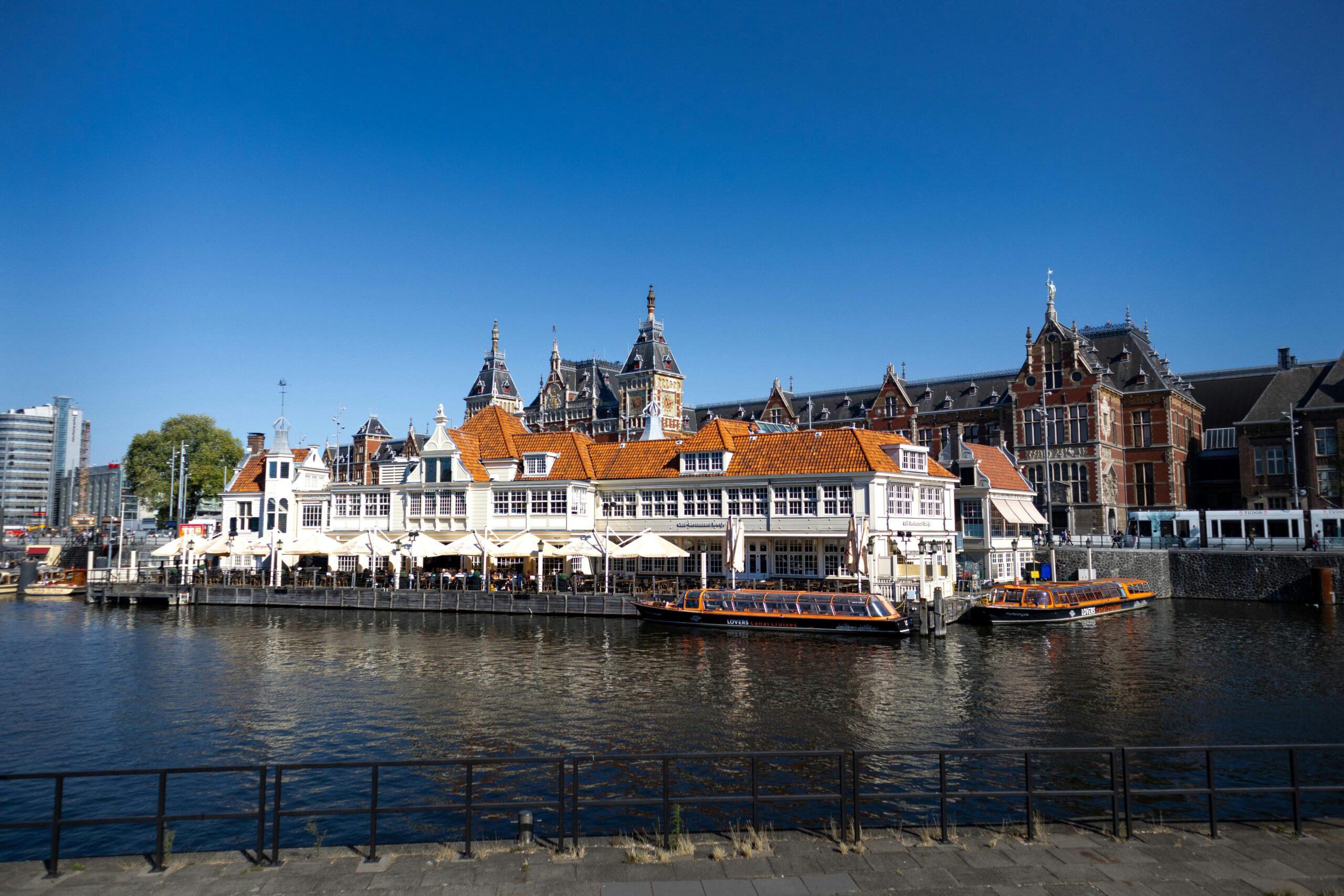Amsterdam canal scene with orange-roofed waterfront buildings and tour boats – is the netherlands cheaper then germany