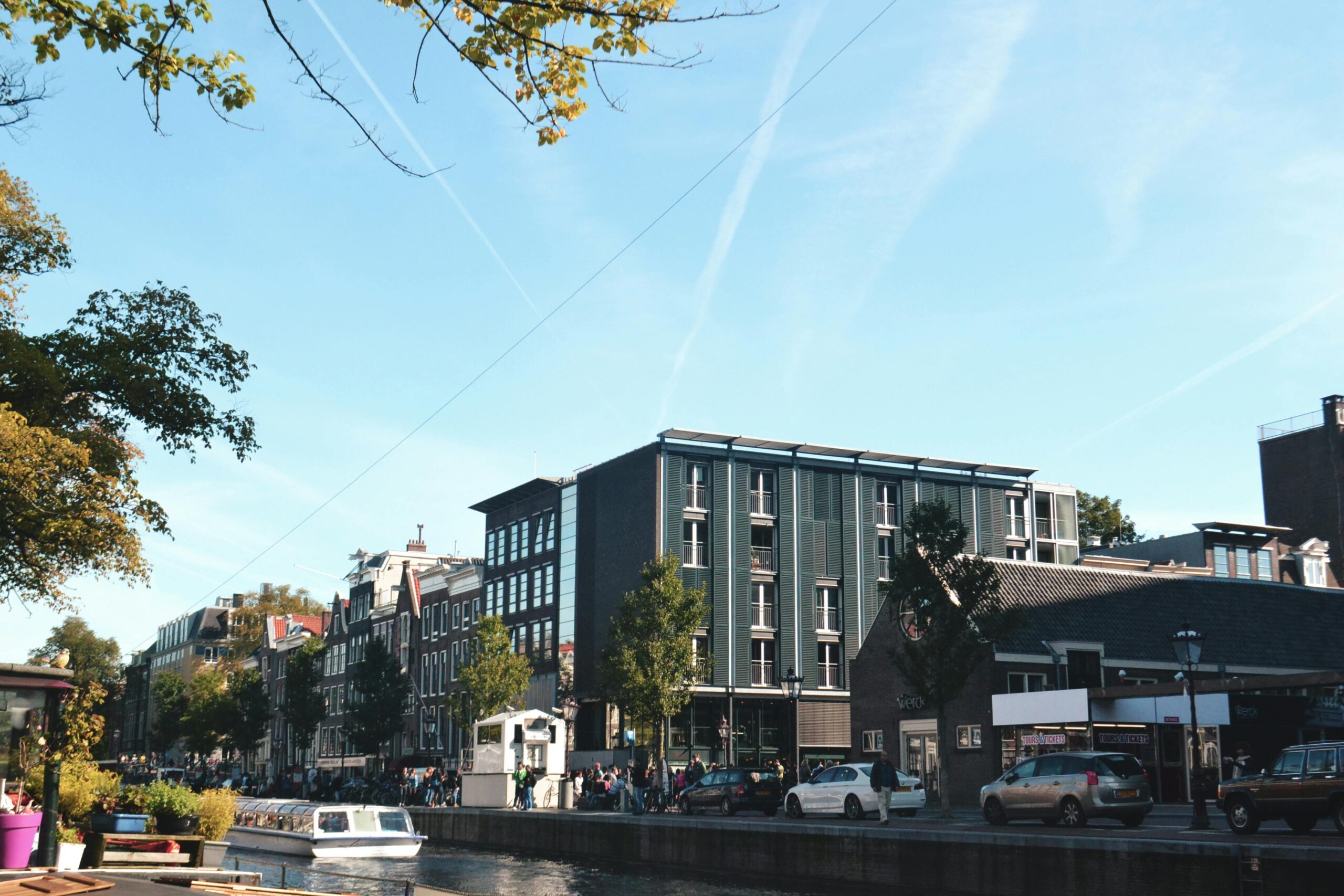 Street view of Amsterdam with modern and traditional buildings along a canal — illustrating urban lifestyle while questioning “is Netherlands expensive?”