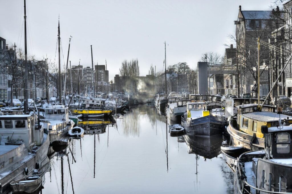 Historic houseboats moored on a narrow Amsterdam canal in winter, capturing picturesque canal life in the Netherlands.