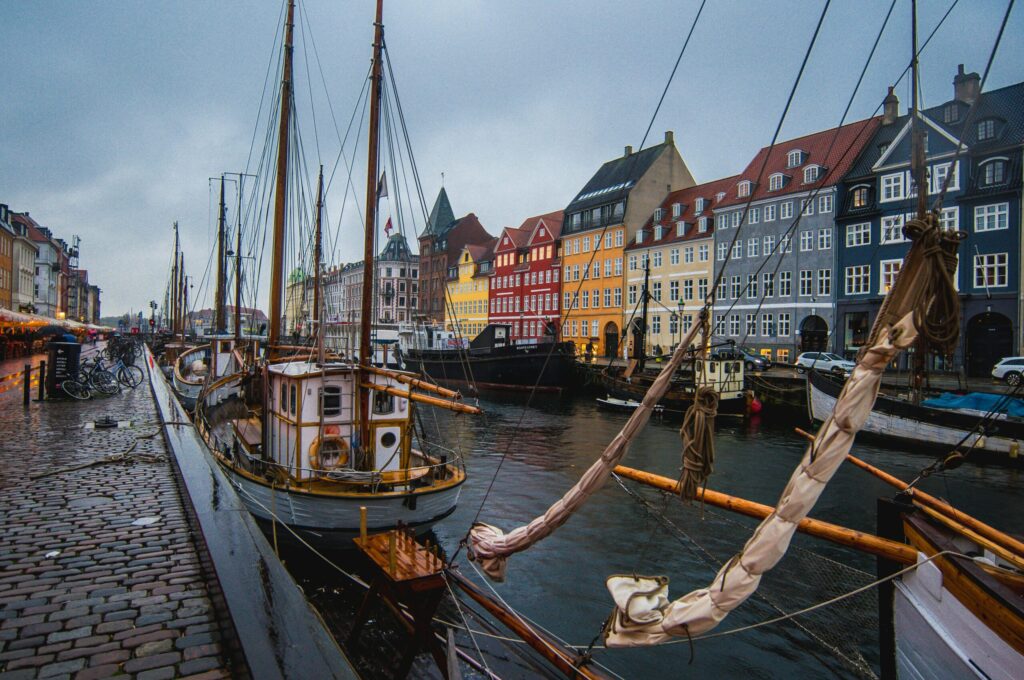 Picturesque waterfront scene in Nyhavn, Copenhagen with boats and colorful houses, representing the charm and atmosphere of living in Denmark.