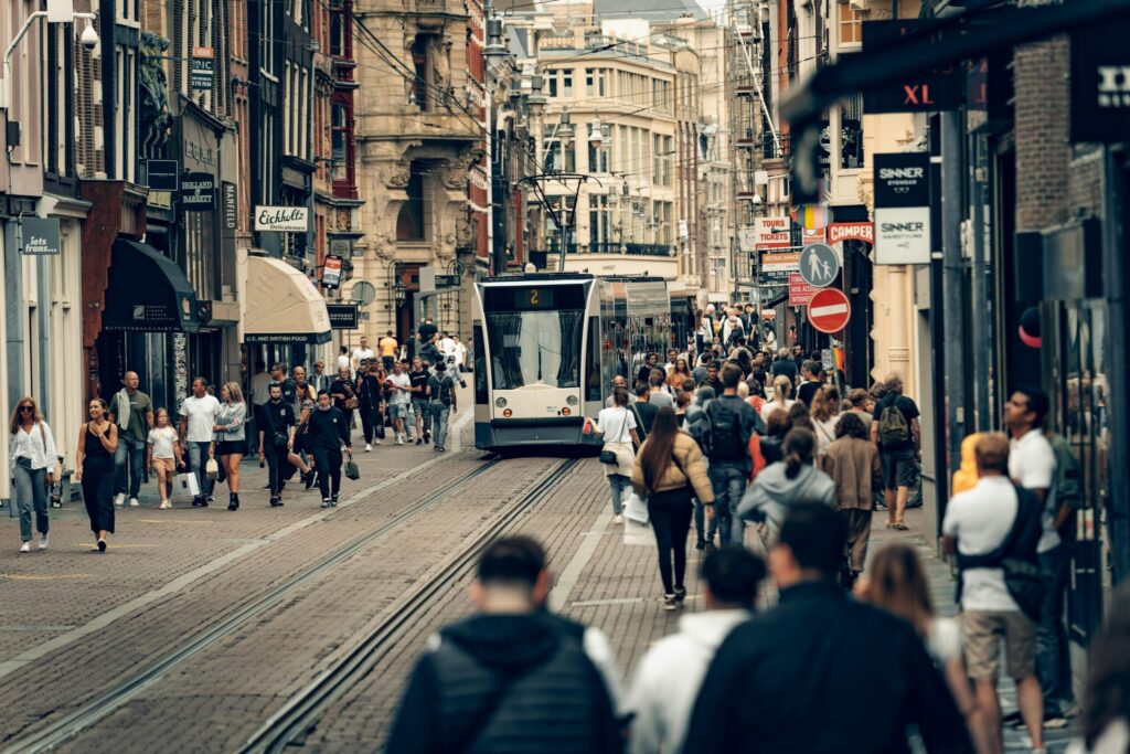 Busy Dutch city street with tram and people shopping – reflecting urban life differences when living in France vs Netherlands