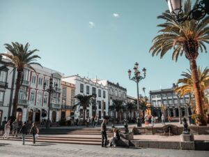 Sunny Spanish plaza with palm trees and historic buildings, capturing the vibrant outdoor lifestyle and Mediterranean charm of living in Spain.