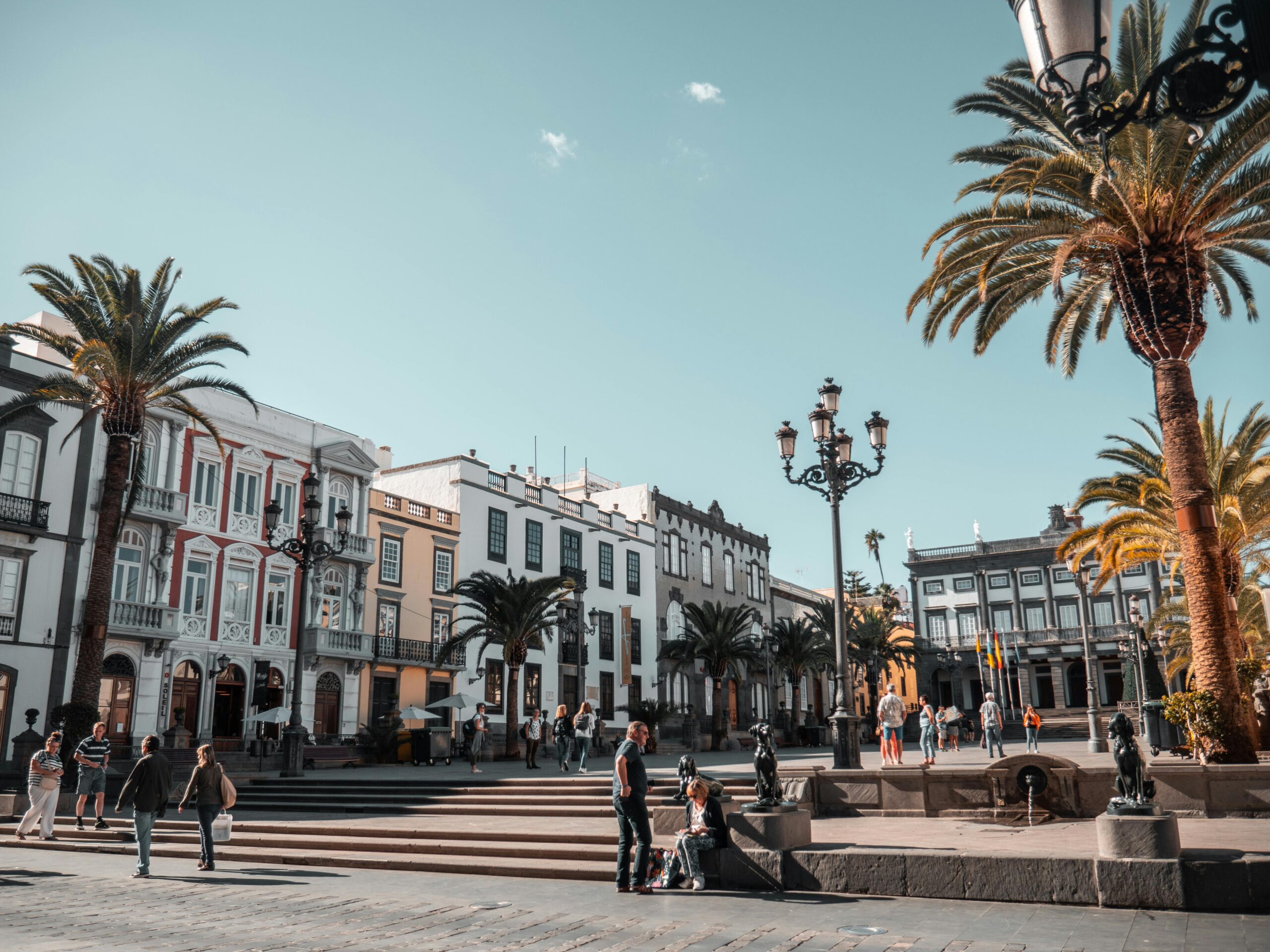 Sunny Spanish plaza with palm trees and historic buildings, capturing the vibrant outdoor lifestyle and Mediterranean charm of living in Spain.