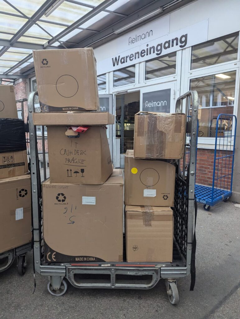 Pallet stacked with sealed cardboard boxes outside a warehouse entrance, prepared for moving to Holland from UK.
