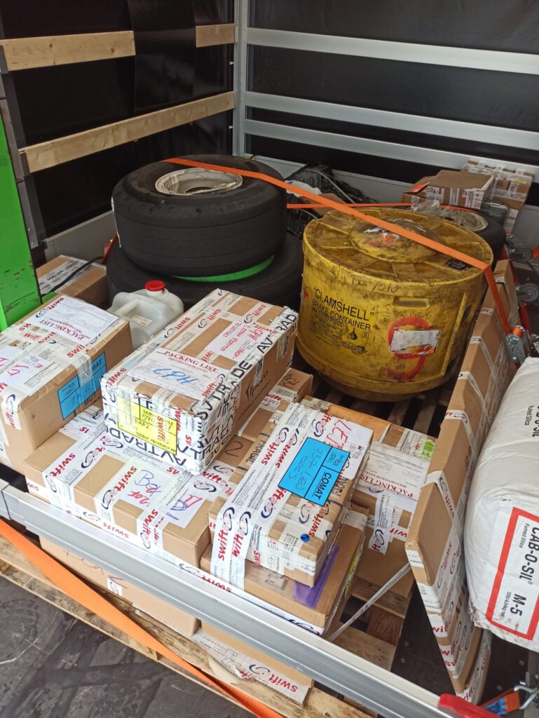Interior of a removals van loaded with packed boxes and equipment secured with orange straps for an office move.