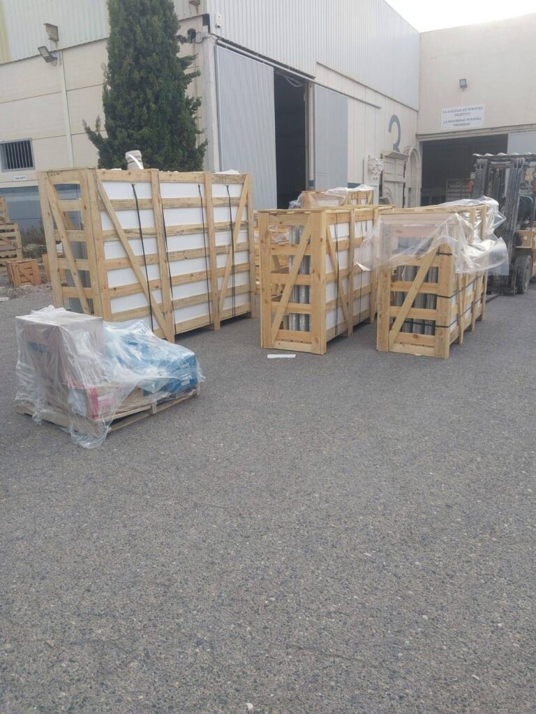 Wooden crates and pallets holding wrapped household items outside a warehouse, ready for relocation to Netherlands.