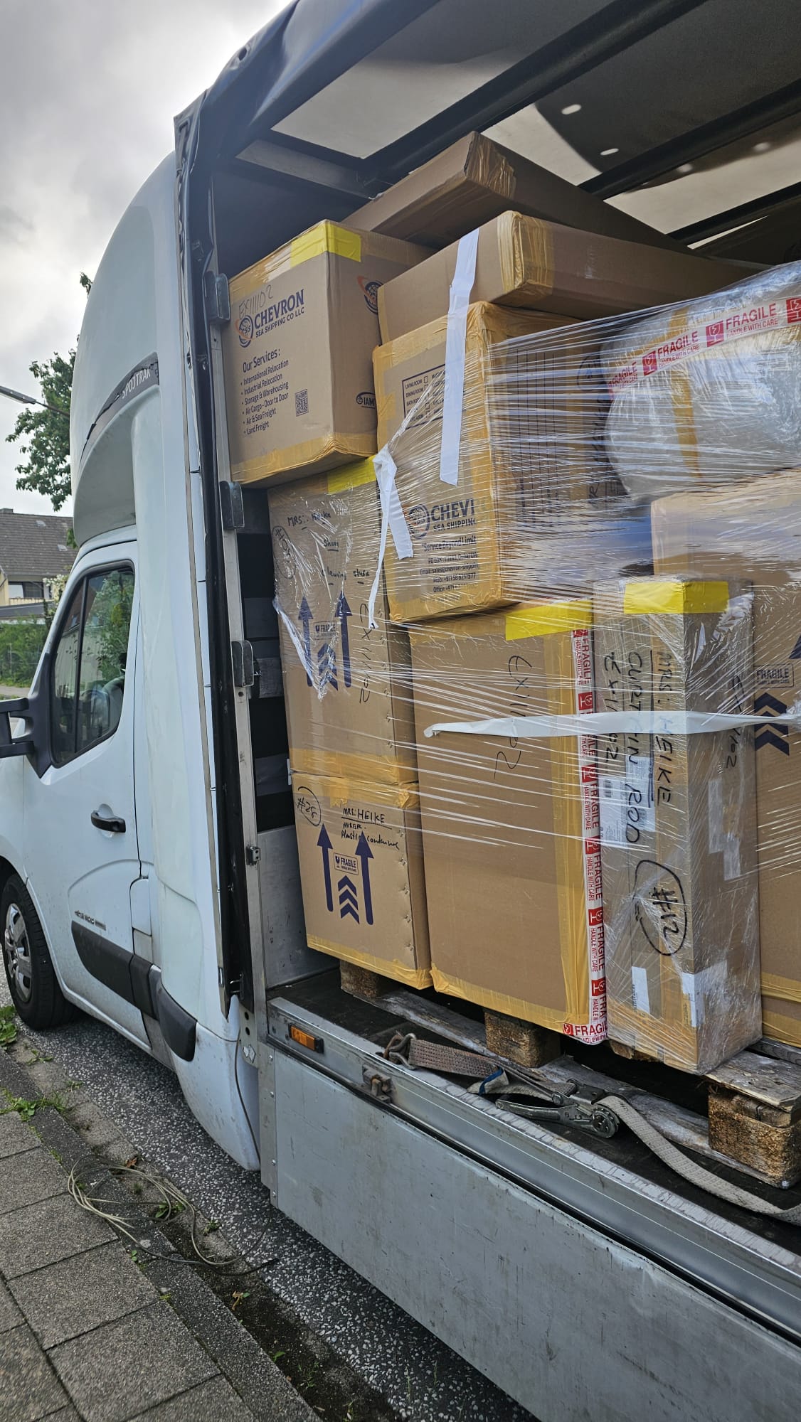 Removal van loaded with packed cardboard boxes and furniture wrapped in plastic, ready for transport from the Netherlands to Germany.