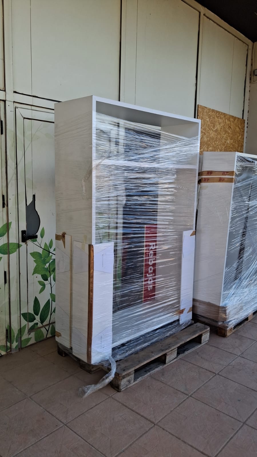 Packed cardboard boxes, bags, and personal items stacked under a spiral staircase, all staged for removals to Holland Netherlands from Spain.