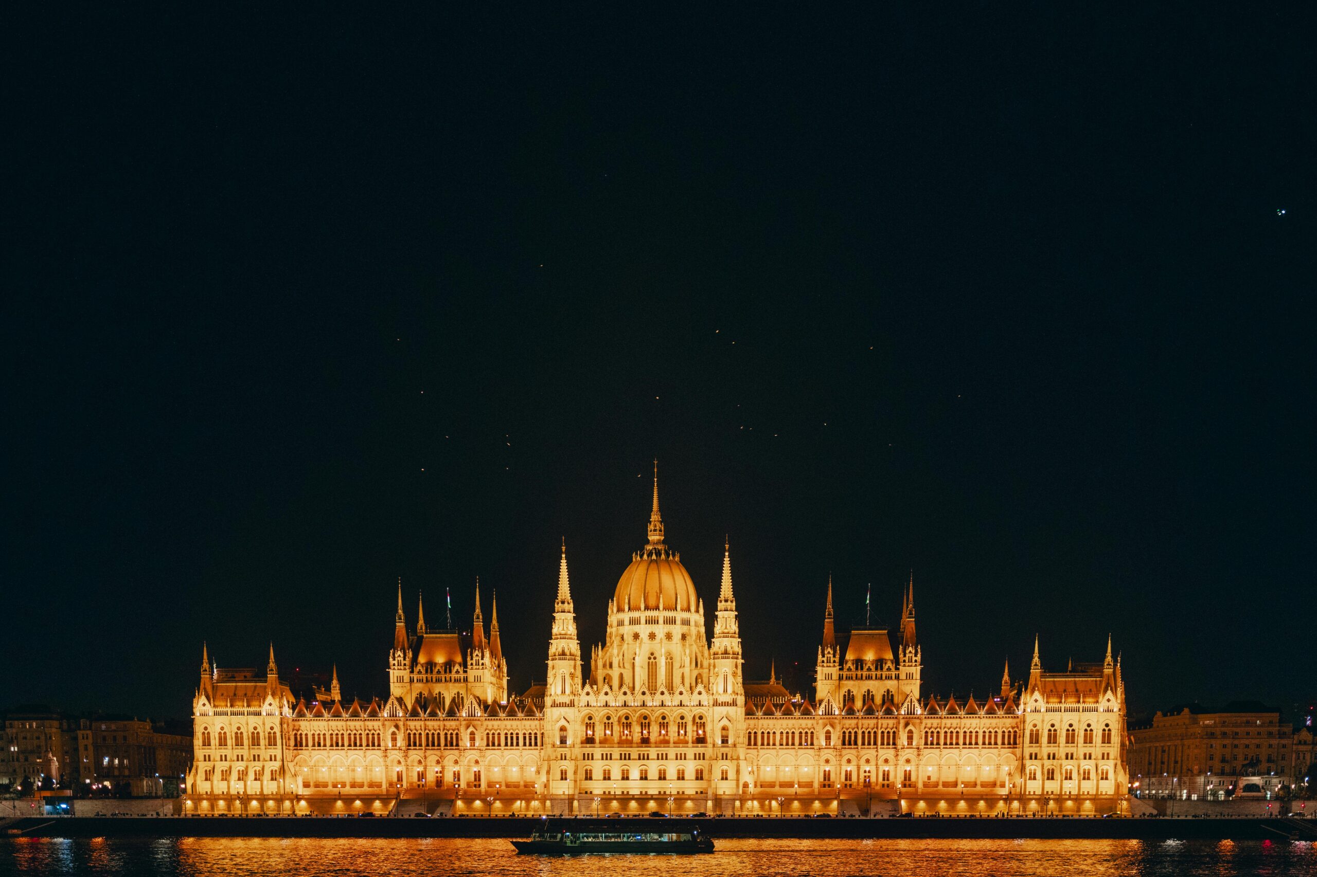 Illuminated Hungarian Parliament Building at night reflecting on the Danube River in Budapest, Hungary.