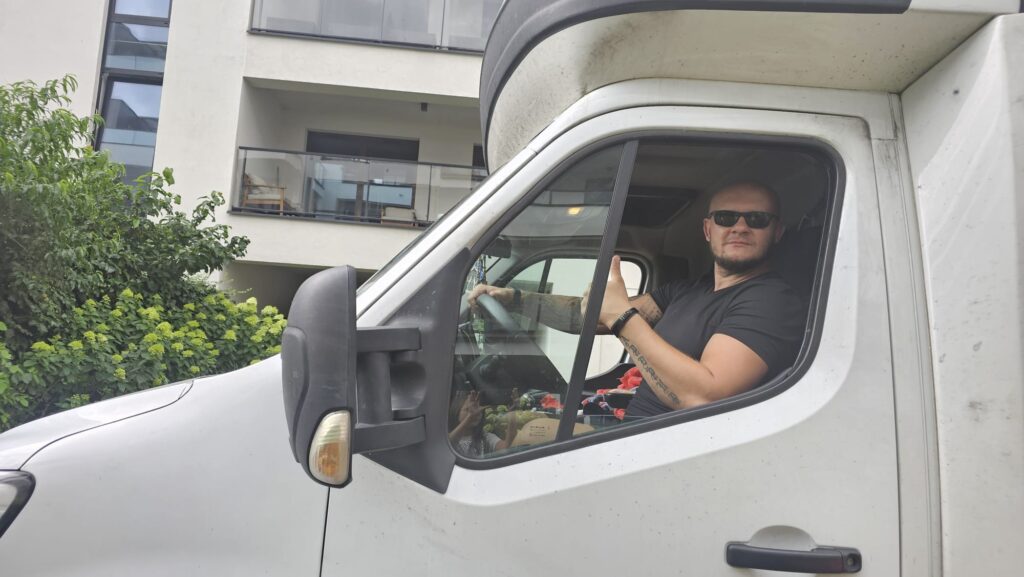 Removals driver sitting in a white box van outside a modern apartment building, ready to start a job