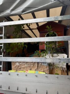 Open sided removal truck loaded with plants, furniture and household items, ready for relocation from Germany to Italy.