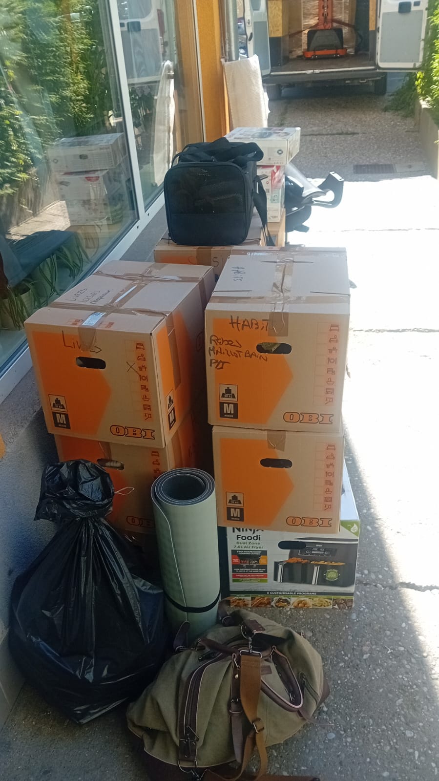 Stack of labelled moving boxes and bags ready for collection outside a building, showing a European relocation in progress with VANonsite international removals.
