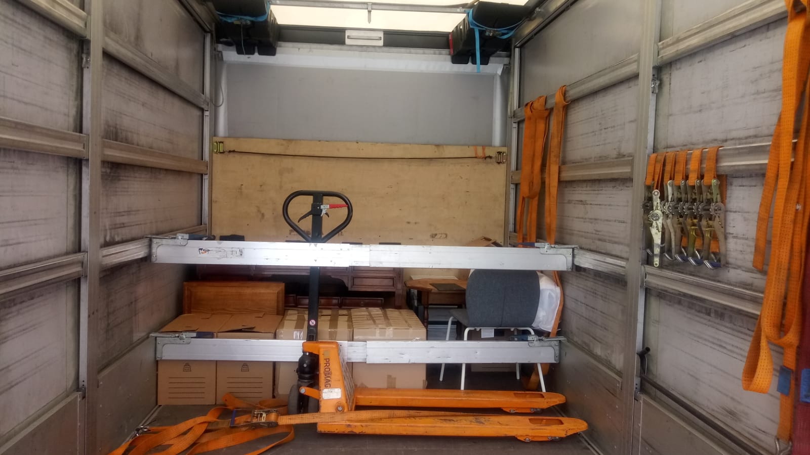 Interior of a professional moving truck with pallet jack, boxes and securing straps prepared for safe international removals with VANonsite.