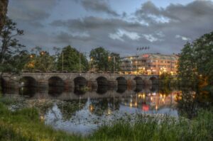 Evening view of a European city bridge and riverside hotel with lights reflected in the water, illustrating seamless European relocations and international removals with VANonsite.