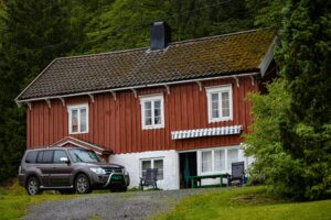 Traditional red Scandinavian house with parked SUV in front, representing a quiet rural home reached through European relocations and international removals with VANonsite.