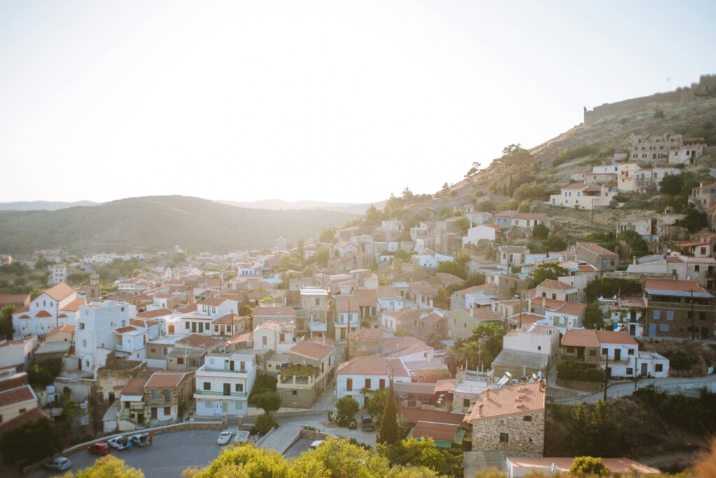 Sunlit hillside village with white houses and red tiled roofs stretching across a mountain slope at golden hour