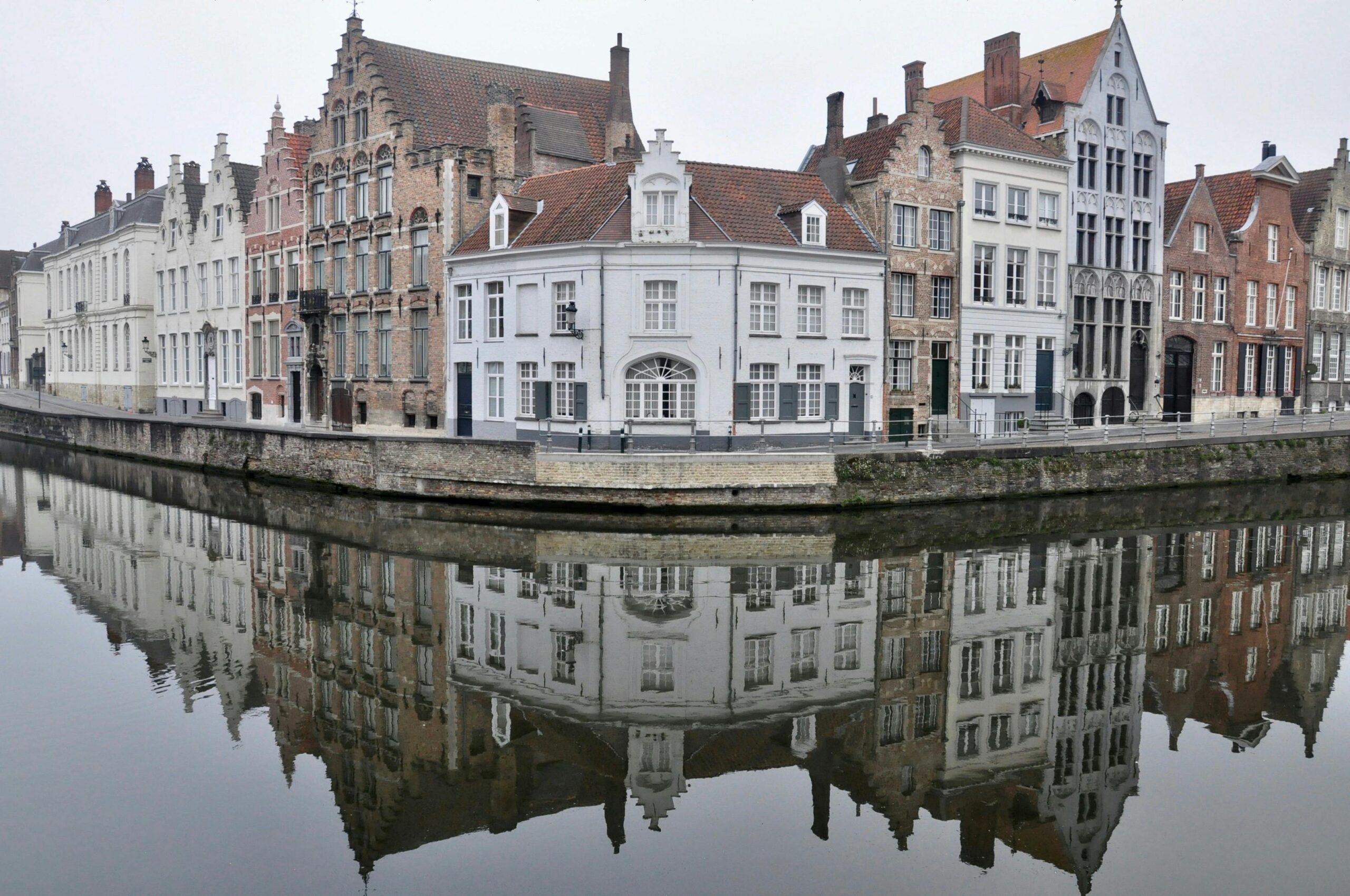 Case storiche a capanna riflettute nel canale in una mattina nebbiosa a Bruges, Belgio