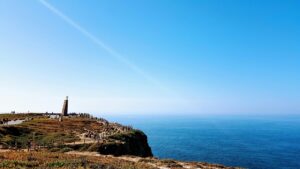Coastal viewpoint with cliffs and walking paths overlooking the ocean under a bright blue sky