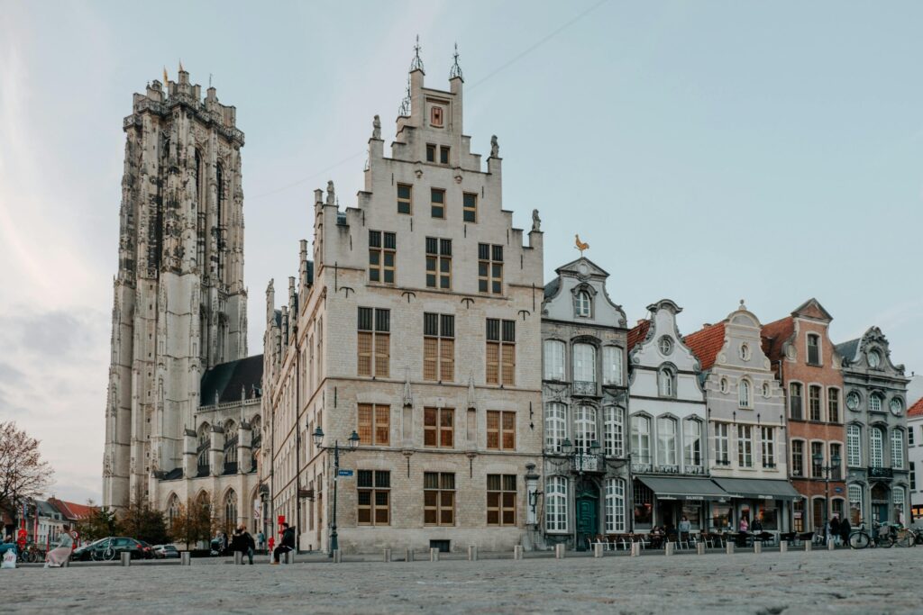 Historic square in Mechelen Belgium with Saint Rumbold’s Cathedral tower and traditional townhouses at dusk, illustrating life after moving to Belgium with VANonsite European removals