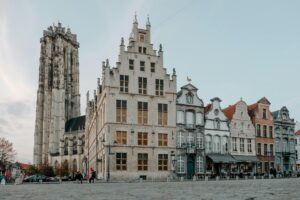 Historic square in Mechelen Belgium with Saint Rumbold’s Cathedral tower and traditional townhouses at dusk, illustrating life after moving to Belgium with VANonsite European removals