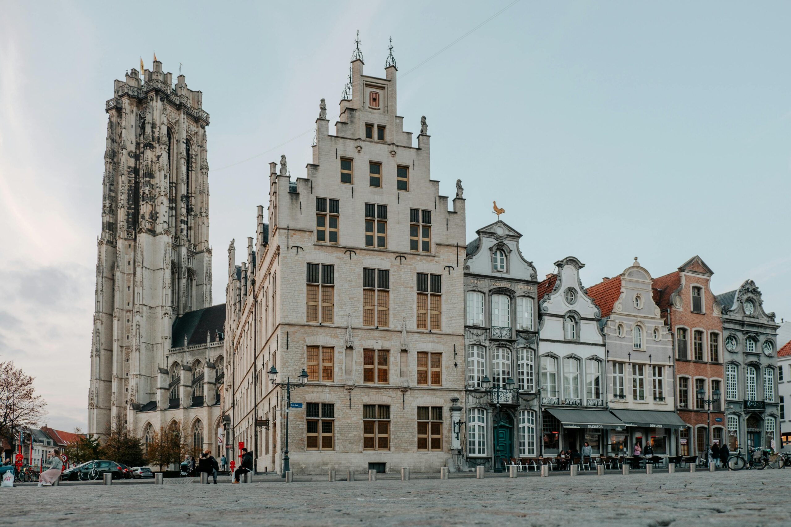 Historic square in Mechelen Belgium with Saint Rumbold’s Cathedral tower and traditional townhouses at dusk, illustrating life after moving to Belgium with VANonsite European removals