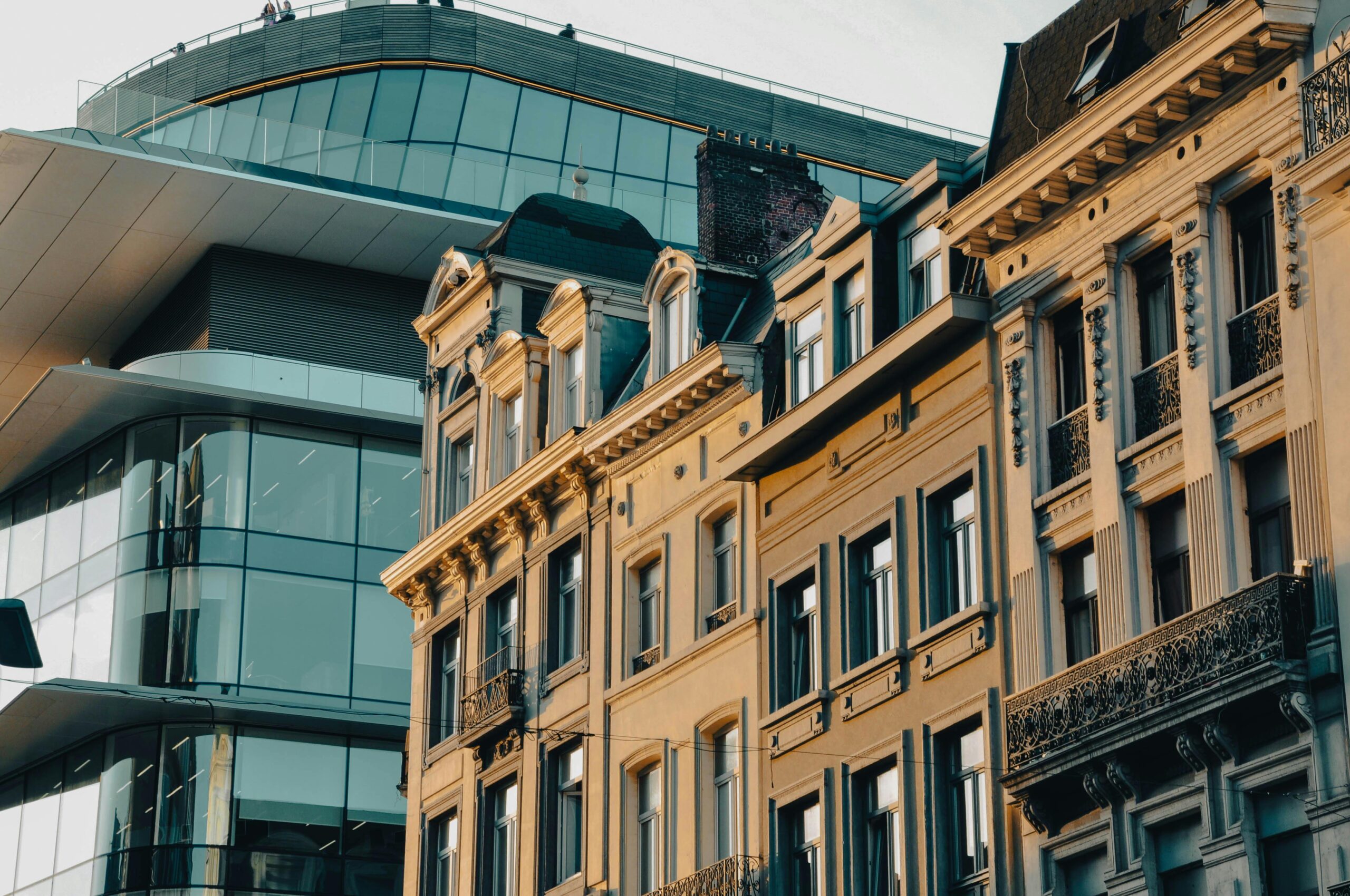 Traditional Brussels townhouses next to a modern glass office building, showing the mix of old and new architecture you can enjoy after moving to Belgium with VANonsite European removals