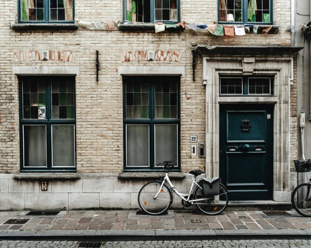 Bicycle parked outside a traditional brick townhouse in Belgium, showing everyday street life you can enjoy after moving to Belgium with VANonsite European removals