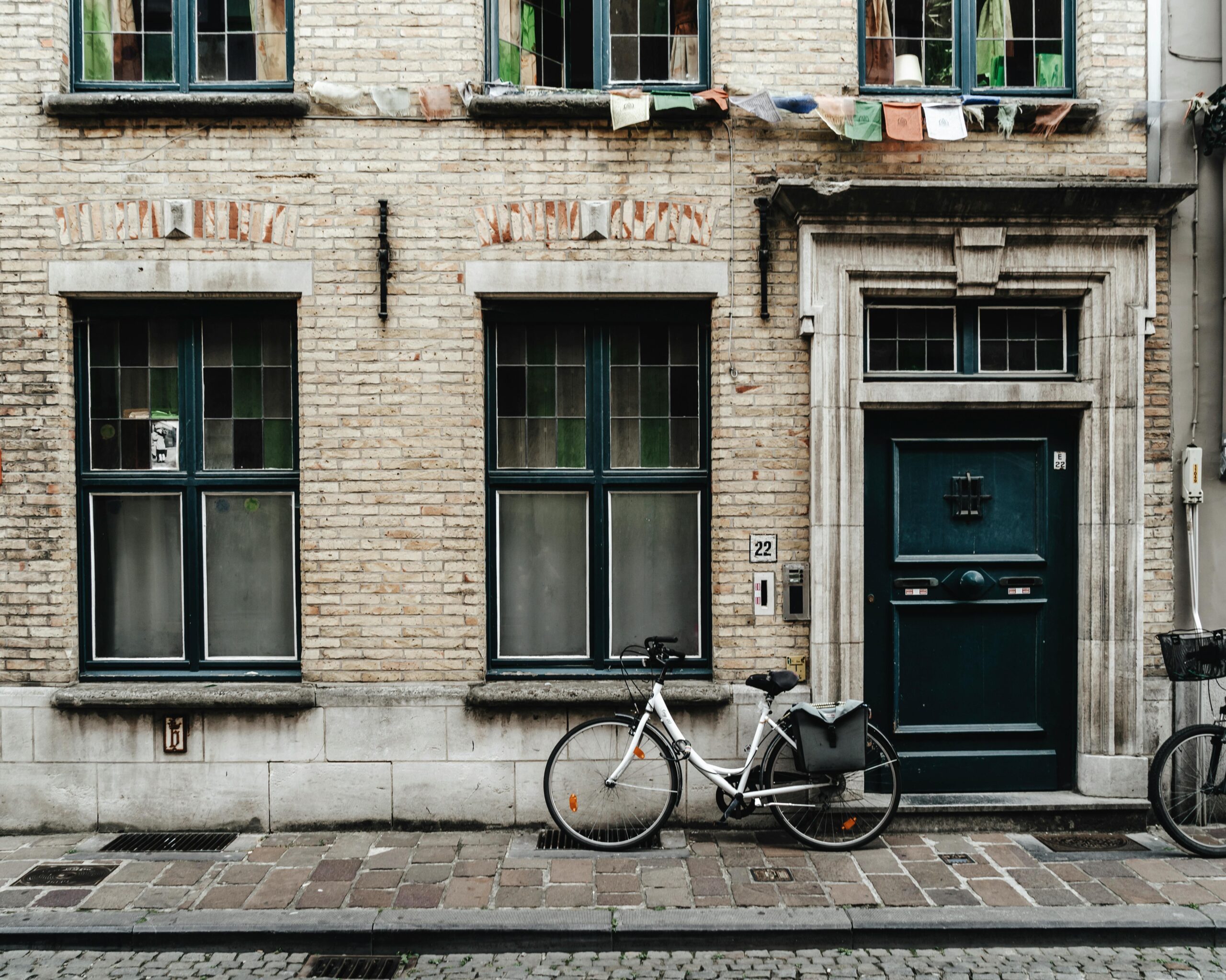 Bicycle parked outside a traditional brick townhouse in Belgium, showing everyday street life you can enjoy after moving to Belgium with VANonsite European removals