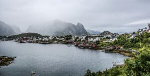 Scandinavian coastal village with red and white houses on a misty bay, showing a remote European destination for international removals with VANonsite.