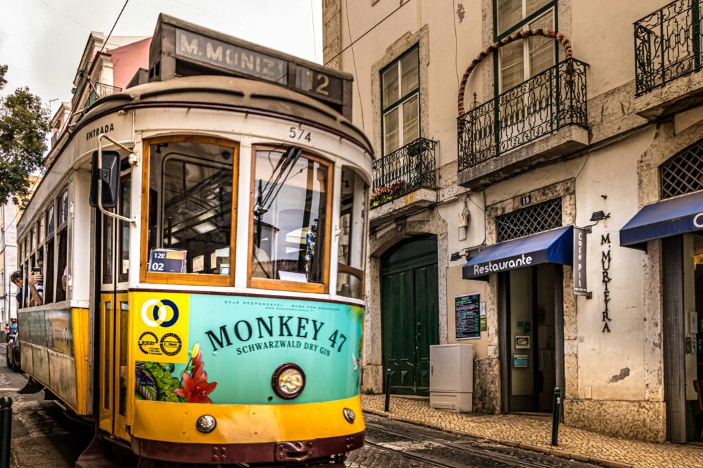 Vintage yellow tram passing through a historic European street with balconies and restaurants