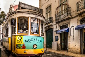 Vintage yellow tram passing through a historic European street with balconies and restaurants