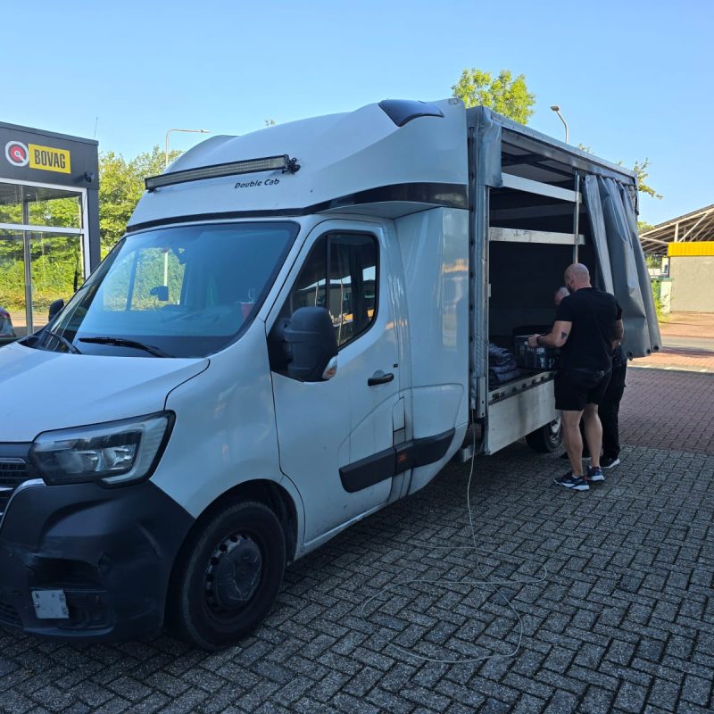 Two 1way movers loading a white Renault moving van from the side in front of a building