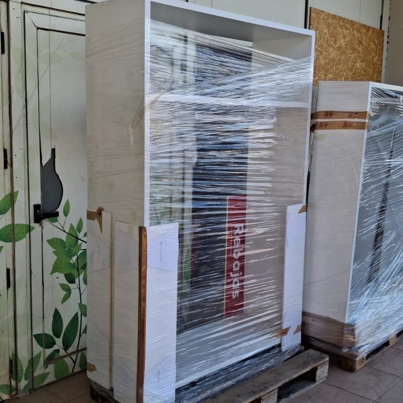 Packed cardboard boxes, bags, and personal items stacked under a spiral staircase, all staged for removals to Holland Netherlands from Spain.