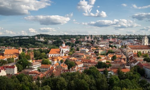 The Vilnius city surrounded by buildings and greenery under sunlight and a cloudy sky in Lithuania